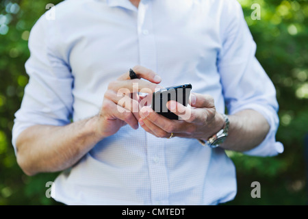 Midsection of man using cell phone Stock Photo