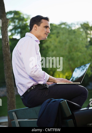 businessman working on laptop while sitting on bench Stock Photo