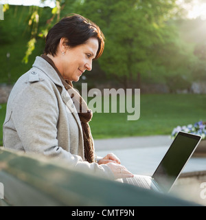 Smiling mature woman using laptop Stock Photo