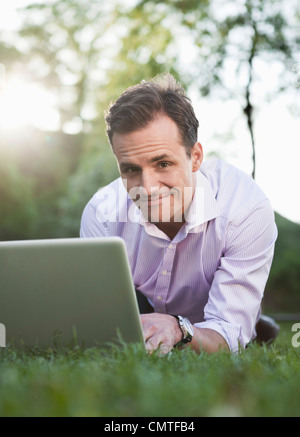 Man using laptop while lying on grass Stock Photo