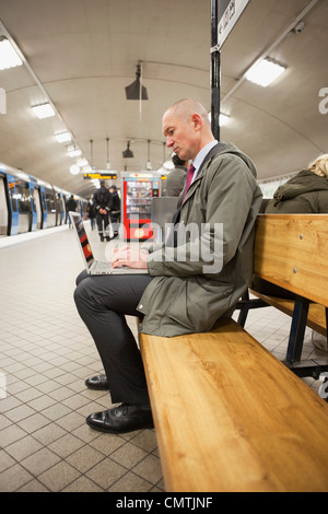 Man on platform using laptop Stock Photo