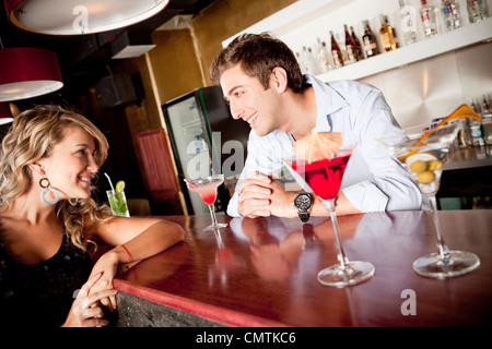 Hispanic woman drinking cocktail talking to bartender Stock Photo