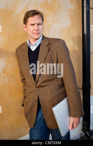 Man in jacket leaning against wall Stock Photo