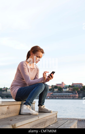 Woman sitting and using cell phone Stock Photo
