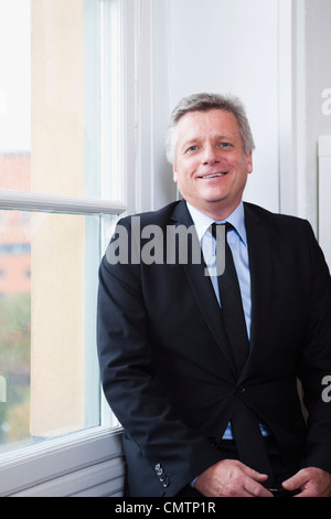 Portrait of businessman holding mobile phone looking at camera Stock Photo