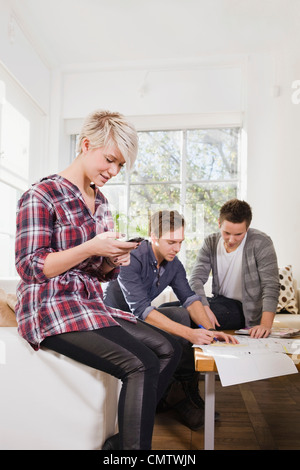Woman using mobile phone and friends studying in the background Stock Photo
