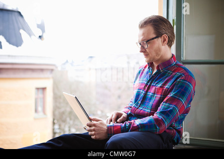 businessman at window using laptop Stock Photo