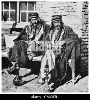 1925 desert Arabs of high degree smoking the water pipe Narghile coffee shop Stock Photo