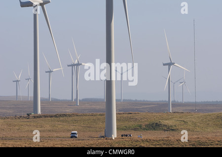 Image showing the size and scale of wind turbines and farm. There is a van and people at the bottom of the first turbine. Stock Photo
