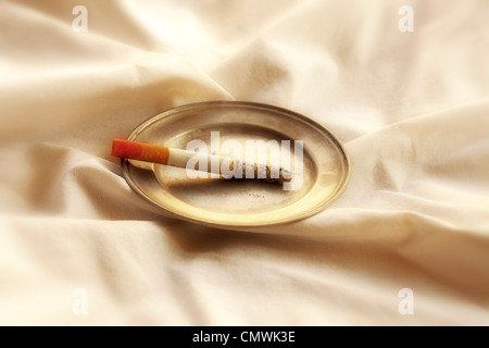 burning cigarette with lipstick on pewter plate Stock Photo