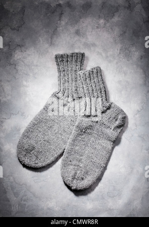 Hand-knitted grey wool socks on grey background Stock Photo