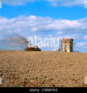 Tractor spreading manure in a field, a derelict house at back, Limagne, Auvergne, France, Europe Stock Photo