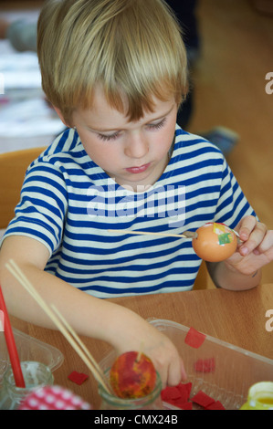 Child Boy painting and decorating eggs for easter Stock Photo