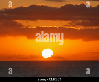 Sunrise through clouds over the sea Stock Photo