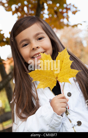 Germany, Huglfing, Girl holding leaf, smiling, portrait Stock Photo