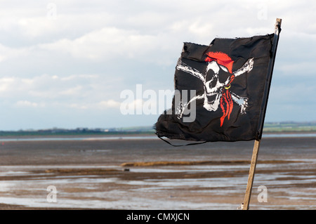 A skull and crossbones pirate flag flying at the coast. Stock Photo