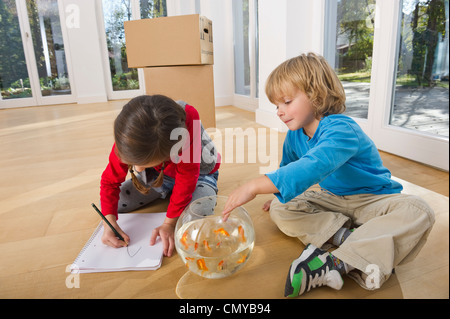 Germany, Bavaria, Grobenzell, Girl drawing and boy playing with goldfish bowl, smiling Stock Photo