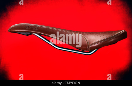 Leather bike saddle made by Charge on a red background. New bicycle seat finished in fake leather for mountain bikes and BMX. Stock Photo