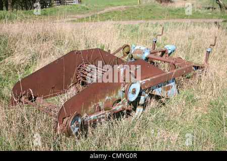 old farm machinery rusting in field Stock Photo