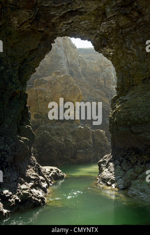 Large natural rock arch and pool on Perranporth beach in Cornwall UK. Stock Photo