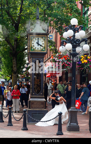 Wedding Couple kissing each other in front of steam clock in Gastown, Vancouver City, Canada, North America Stock Photo