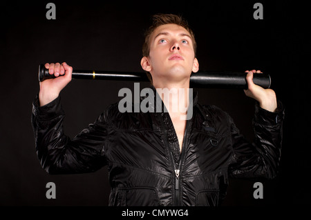 Young man with baseball-bat over black background. Stock Photo