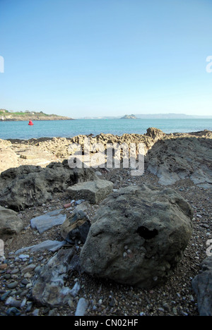 A view of Plymouth Sound and Drakes Island with a rock pool and rocks in the foreground. Stock Photo