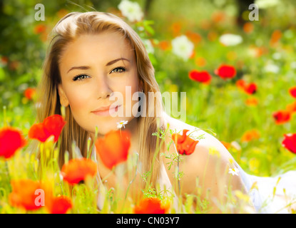 Young beautiful girl enjoying on the poppy flowers field, outdoor portrait, summer fun concept,woman in the floral garden Stock Photo
