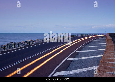 Car light trails on coastal highway.  Captain Cook Highway between Port Douglas and Cairns, Queensland, Australia Stock Photo