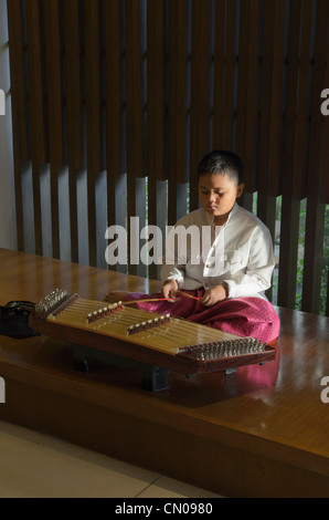 A young Thai boy plays a traditional khim instrument, Phuket, Thailand Stock Photo