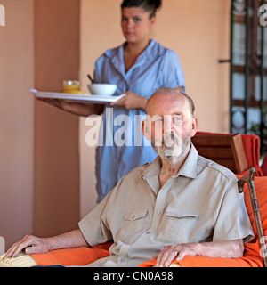 senior with carer or nurse bringing meal Stock Photo