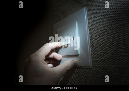 MANS HAND FINGER WITH DOMESTIC LIGHT SWITCH RE ELECTRICITY BILLS FUEL COSTS THE ENVIRONMENT ELECTRIC FOSSIL FUELS SWITCHING OFF Stock Photo