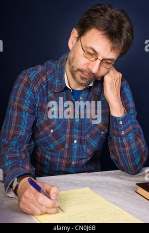 Journalist surrounded by books takes notes on paper Stock Photo