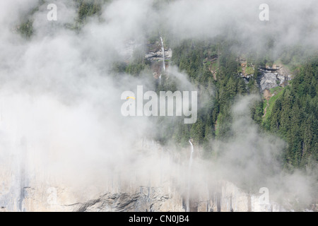 Skydiver / parachutist soaring by a waterfall shrouded in fog. Staubbachfall, Lauterbrunnen Valley, Bern, Switzerlland. Stock Photo