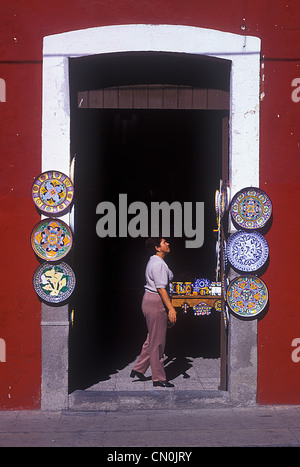 Woman looking at colorful plate display in Mexican shop Stock Photo