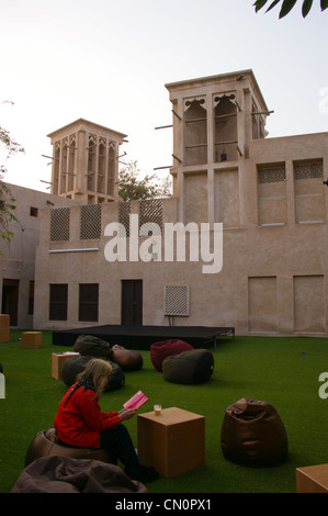 Windtowers in Bastakiya, at sunset, Dubai, United Arab Emirates with a woman reading a book Stock Photo