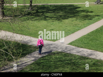 A woman at a crossroads path, making a choice about which way to go. Stock Photo
