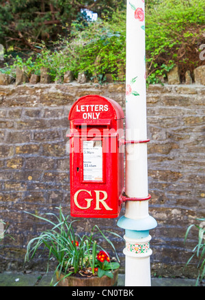 Bright red post box attached to a white decorated and painted lamppost in Frome Somerset inscribed GR (George Rex) for George V Stock Photo