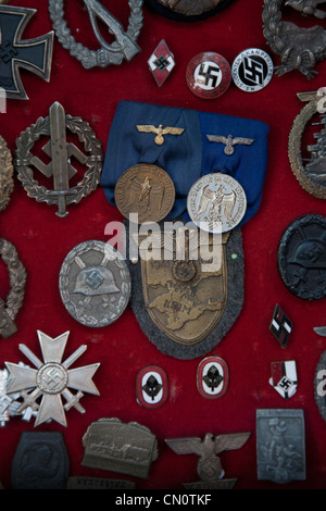 Nazi and SS insignia, badges and medals displayed on a red background, for sale in an antiques shop in Trieste Italy Stock Photo