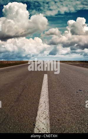 Beautiful sprig clouds over a highway road that stretches to infinity Stock Photo