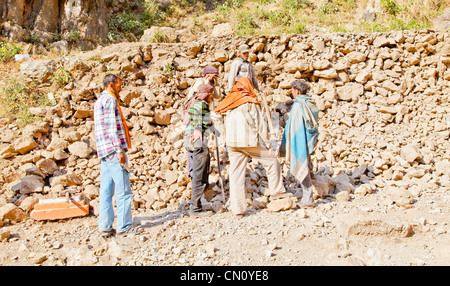wall building gang along the public foot path to Shiv Kodi hindu temple having a break from breaking rocks Stock Photo