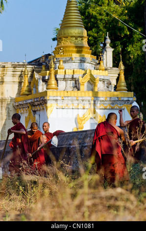 Group of young monks clearing ground around temple, Bagan, Myanmar Stock Photo