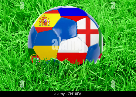 Soccer ball on grass field background. Ball filled with euro 2012 countries flags colors. Stock Photo