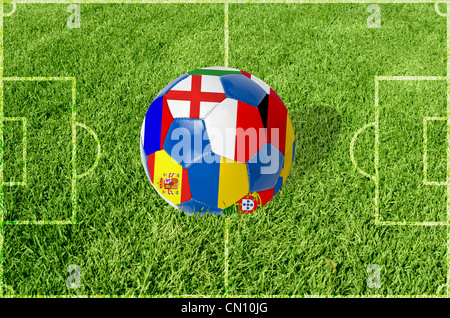 Soccer ball on grass field background. Ball filled with euro 2012 countries flags colors. Stock Photo