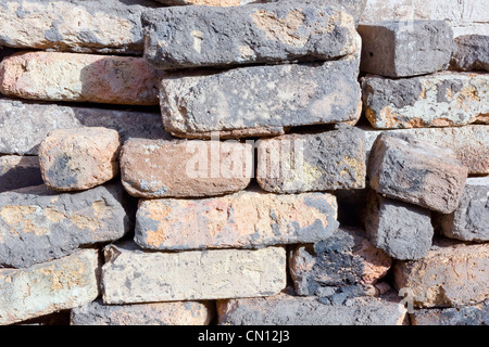 The wall is made of ancient clay red bricks background. Sunny day Stock Photo