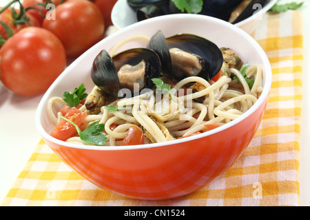 Spaghetti with tomatoes, mussels and parsley on a light background Stock Photo