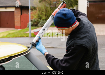 Man applies glue before fitting a new windscreen to a car Stock Photo