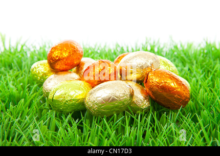 Golden chocolate easter eggs on grass over white background Stock Photo