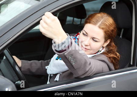 Pretty young Russian Caucasian woman sitting in vehicle and shaking hers fist Stock Photo