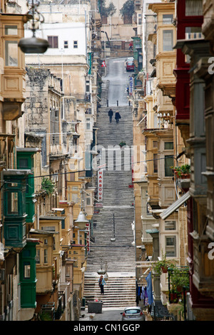 Street scene with covered wooden balconies and long flights of stairs on a hill in Valletta, Malta Stock Photo